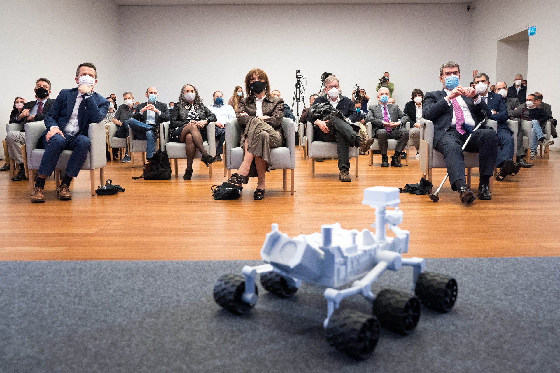 Conectamos con la señal de la NASA. El auditorio se prepara para el momento cumbre. Una maqueta de Percy preside la sala.